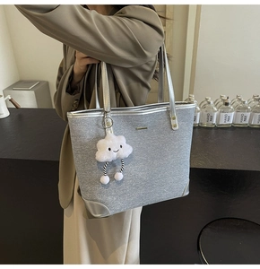 Detail of silver canvas tote bag with shiny texture and white fluffy cloud charm