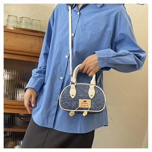 Dettaglio della borsa a tracolla in denim con manico a contrasto e patch a cartone