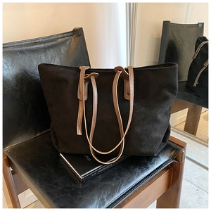 Macro detail of large black tote bag with brown leather straps on a vintage chair