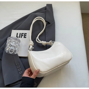 Detail of cream white faux leather shoulder bag with unique knotted strap on a gray blazer