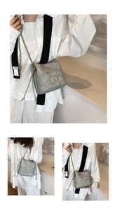 Close-up of grey marble pattern bucket bag with gold chain and triangle logo detail