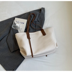 Minimalist white woven PU tote bag with dark brown handles on a grey blazer backdrop