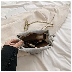 Close-up of small gray fabric bucket bag interior with drawstring and gold chain strap