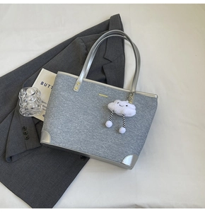 Detailed view of gray denim tote bag with silver leather handles and plush cloud charm