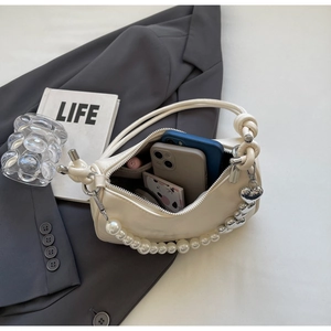 Detail view of cream white handbag with pearl handle and heart charm interior space