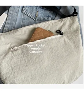 Detail shot of the beige nylon crossbody bag featuring an external zipper storage pocket