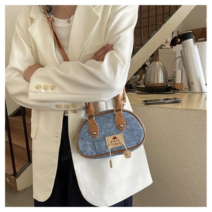 Dettaglio ravvicinato di una borsa a cuscino in denim blu con toppa fashion e manici in marrone