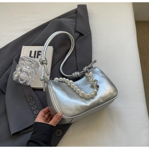 Detail of silver metallic bag with pearl chain decoration on a minimalist background