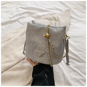 Detail of grey drawstring bucket bag with marble texture and golden chain strap