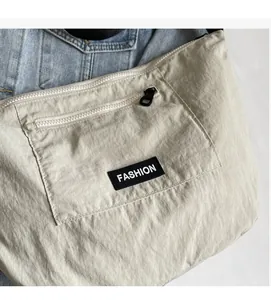 Detailed macro view of the soft beige nylon fabric and Fashion label on the crossbody bag