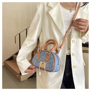 Dettaglio mini borsa in denim con contrasto in pelle marrone e toppa a cartone