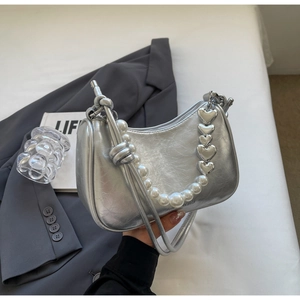 Detail of silver crescent bag featuring pearl heart chain and cracked texture finish