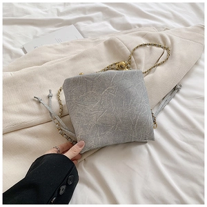 Detail of grey denim texture drawstring bucket bag with golden chain strap