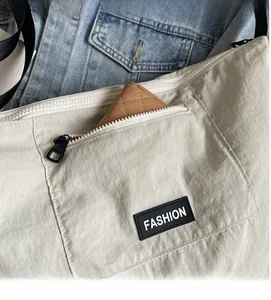Close-up of beige nylon canvas crossbody bag with functional zipper pocket and fashion label
