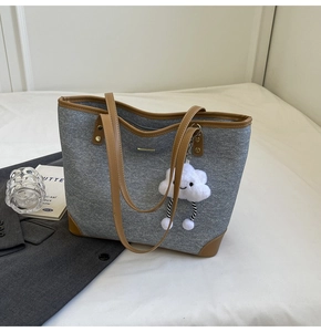 Detail of grey canvas tote with brown leather trim and cute white cloud pendant
