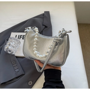 Detail of silver metallic handbag with pearl handle and knotted strap texture