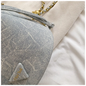 Close-up of blue monogram bucket bag fabric with gold chain strap and chic embroidery