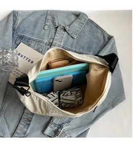Spacious interior of off-white oxford nylon crossbody bag holding tablet and daily items