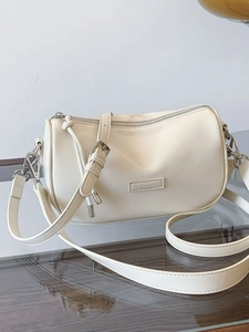 Creamy white cylindrical underarm bag with silver hardware and adjustable strap