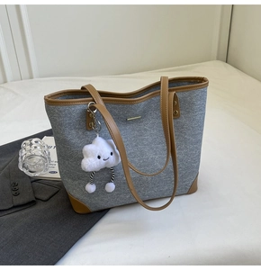 Detail of grey canvas tote bag with brown leather trim and cute plush cloud charm