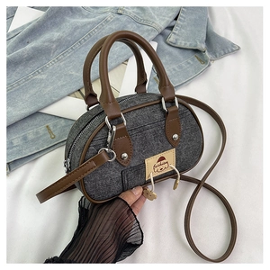 Dettaglio mini borsa ovale in denim con finiture in pelle marrone e patch logo cane
