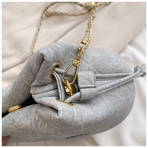 Detailed close-up of light blue fabric drawstring bucket bag with gold chain and hooks