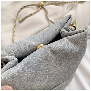 Detail of light blue textured bucket bag with star embossing and gold chain strap