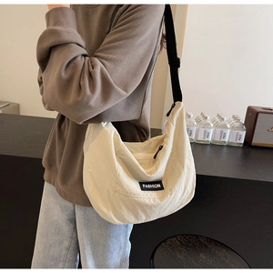 Detail of beige crescent nylon crossbody bag with wide black strap and Fashion patch