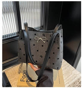 Detail of grey herringbone bucket bag with black polka dots and silver metal bow decoration