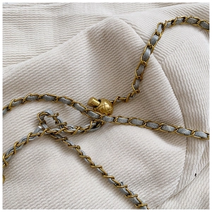 Close-up of golden chain strap with adjustable metal ball on a stylish bucket bag