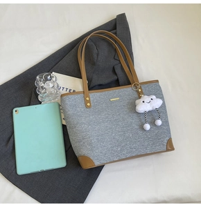 Detail of grey denim tote bag with brown trim, cloud charm and tablet for scale
