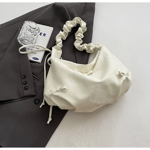 Détail du sac plissé blanc crème avec nœud latéral et bandoulière à volants élégante