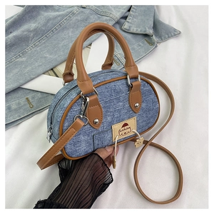 Dettaglio della mini borsa in denim con manici in pelle marrone e toppa con cucciolo