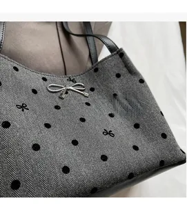 Detail of herringbone fabric tote bag with black polka dots and silver bow charm