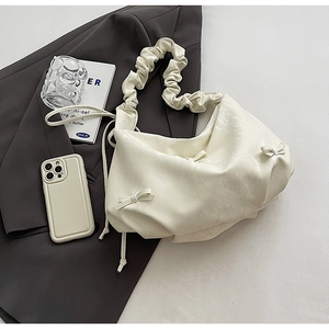 Détail d'un sac à bandoulière plissé blanc crème avec nœuds et bandoulière à volants