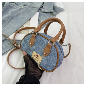 Dettaglio mini borsa a bauletto in denim con finiture in pelle marrone e patch