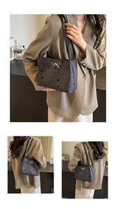 Detail of dark grey canvas bucket bag with star patterns and silver bow accessory