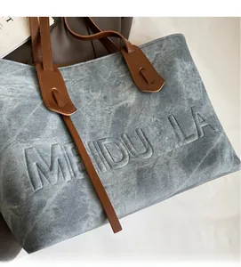Macro detail of MEIDUOLA grey tote bag texture and brown leather shoulder strap