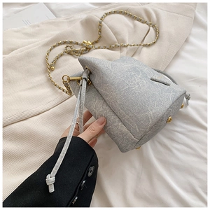 Detail of marble pattern bucket bag with gold metal base feet and drawstring closure