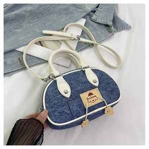 Dettaglio ravvicinato del denim blu e rifiniture in pelle bianca sulla borsa a cuscino