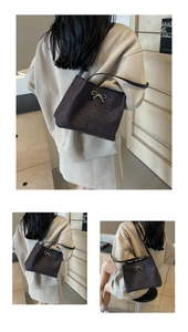 Close-up of dark grey tote bag with red heart embroidery and silver bow detail