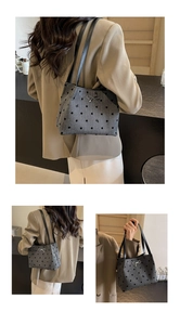 Detail of grey polka dot shoulder bag featuring a silver bow and black leather straps