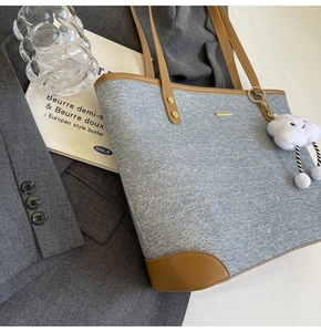 Detail of blue denim tote bag with brown leather trim and cute white cloud charm
