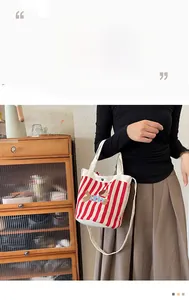 Détail du sac seau en toile à rayures rouges avec broderie de chien et anses blanches
