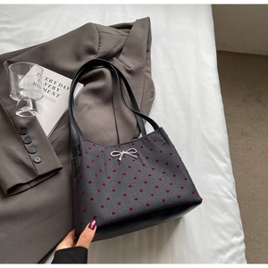 Close-up of heart print bucket bag with silver bow ornament on a textured background
