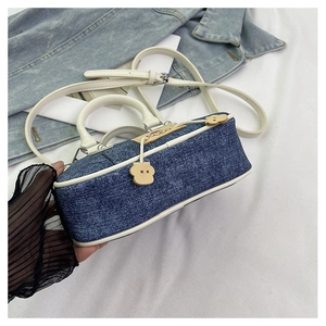 Dettaglio della mini borsa Boston in denim con finiture in pelle bianca e ciondolo