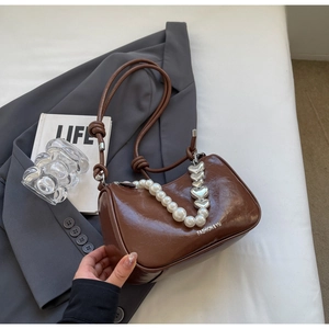 Detailed shot of coffee brown glossy shoulder bag with pearl chain and silver heart pendant
