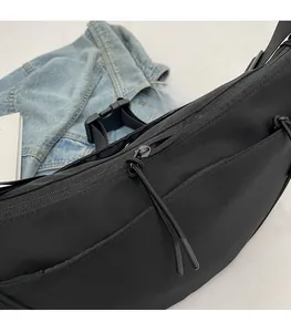 Detail of smooth zipper closure with woven cord puller on black canvas crossbody bag