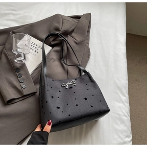 Detail of grey bucket bag with star patterns and a silver metal bow accessory