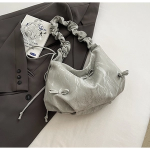 Détail d'un sac plissé vert clair avec nœud décoratif sur une veste sombre